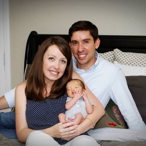 family photo on bed with newborn boy, mom and dad