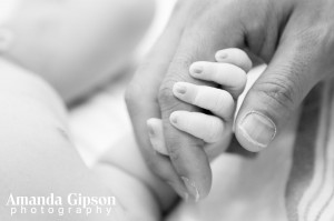 Baby holding tight to parent's finger