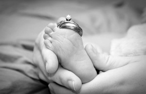 closeup of wedding rings on newborn's toe with parents' hands photo credit Jenny Krafft