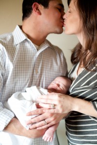 JennaBethPhotography_ Mom and Dad kissing while holding their newborn baby