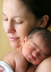 Closeup of mother's face with her sleeping baby on her shoulder