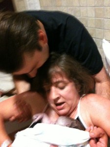 hospital waterbirth dad supporting mom as she brings baby up out of water
