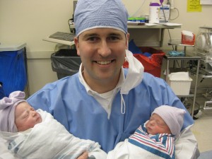 Daddy holding boy and girl twin babies in hospital